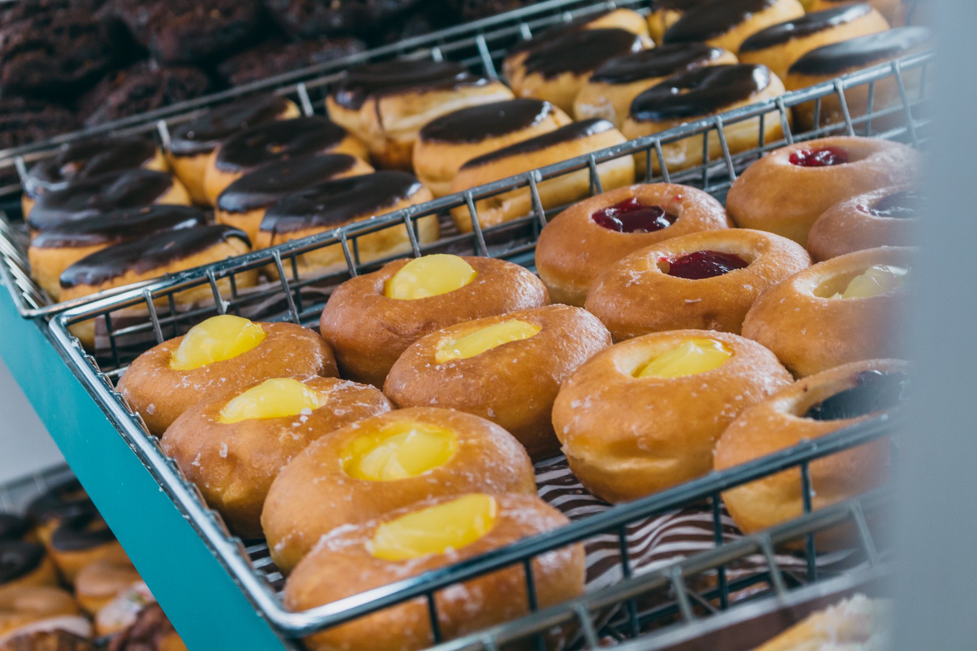 Rows of custard and jam-filled donuts alongside chocolate-glazed donuts on bakery shelves