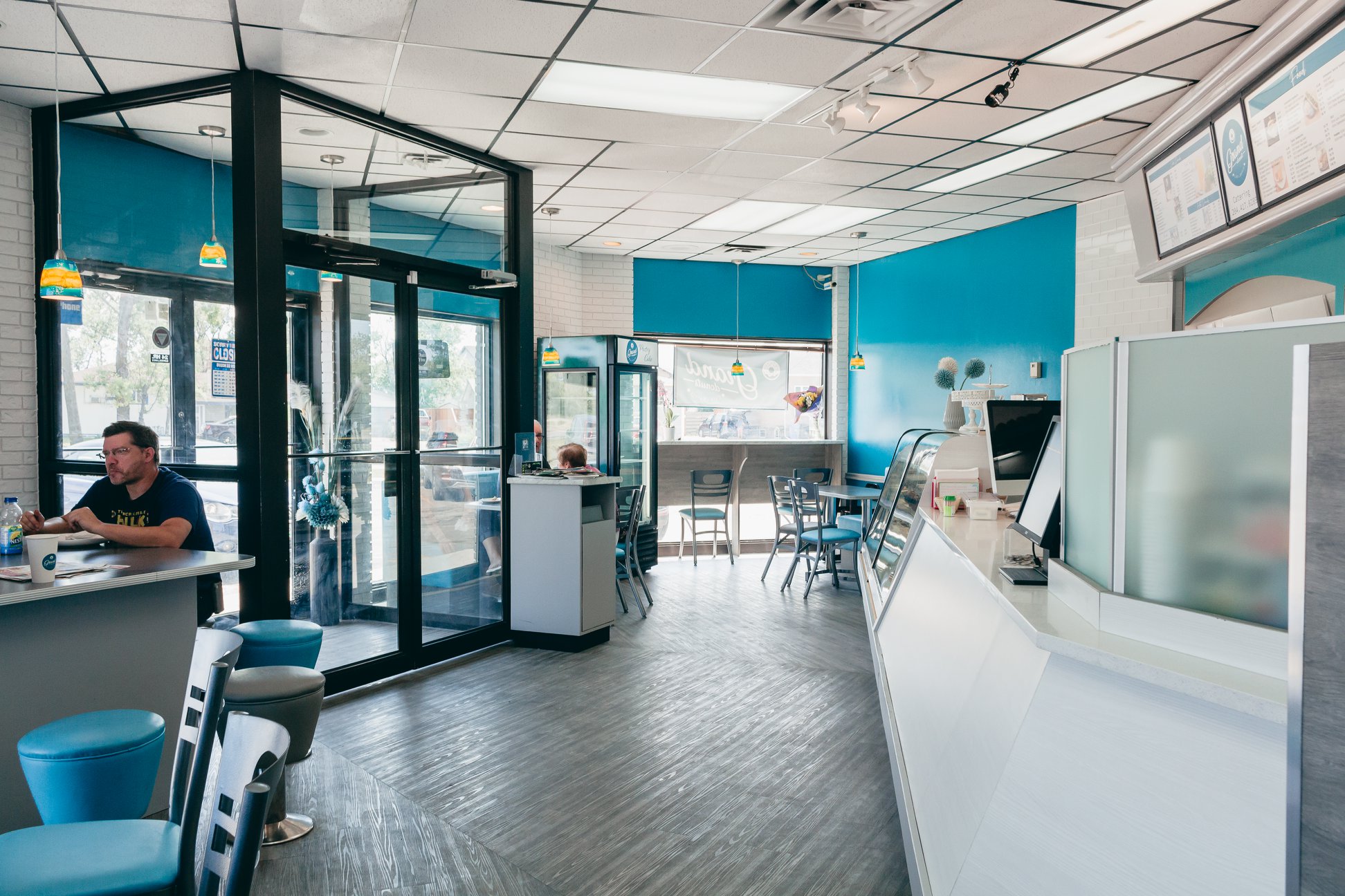 Interior of GrandDonut Cafe showing teal-accented seating area, counter, and entrance