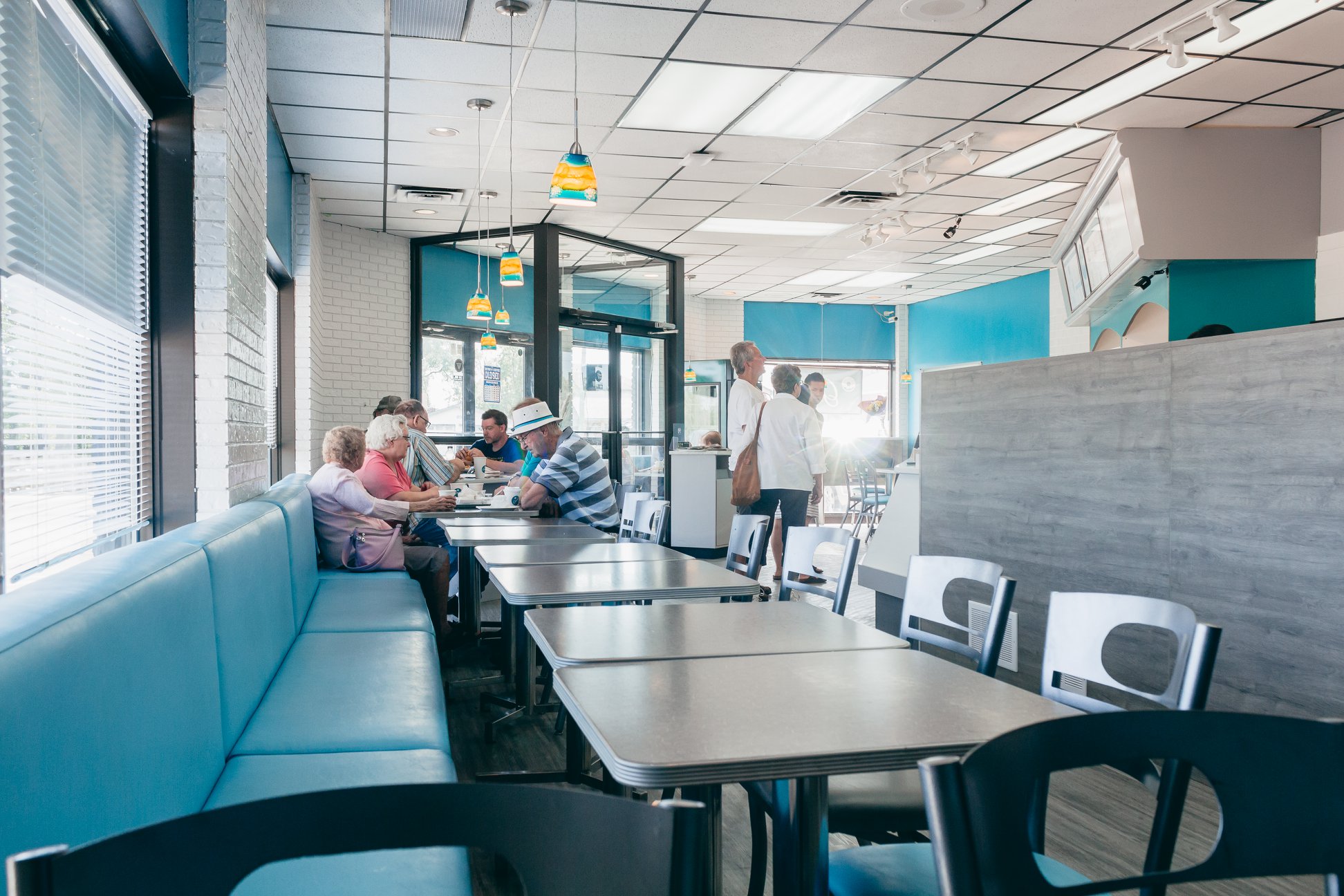 Customers dining in teal booth seating at GrandDonut Cafe with pendant lights